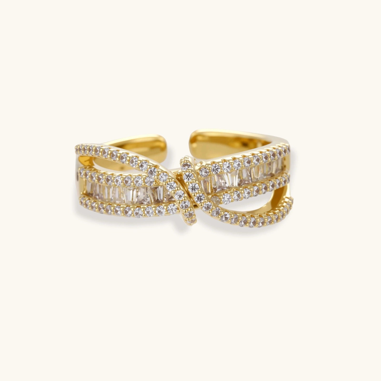Close-up of gold-plated adjustable ring with crossing bands and sparkling zirconia stones on white background.