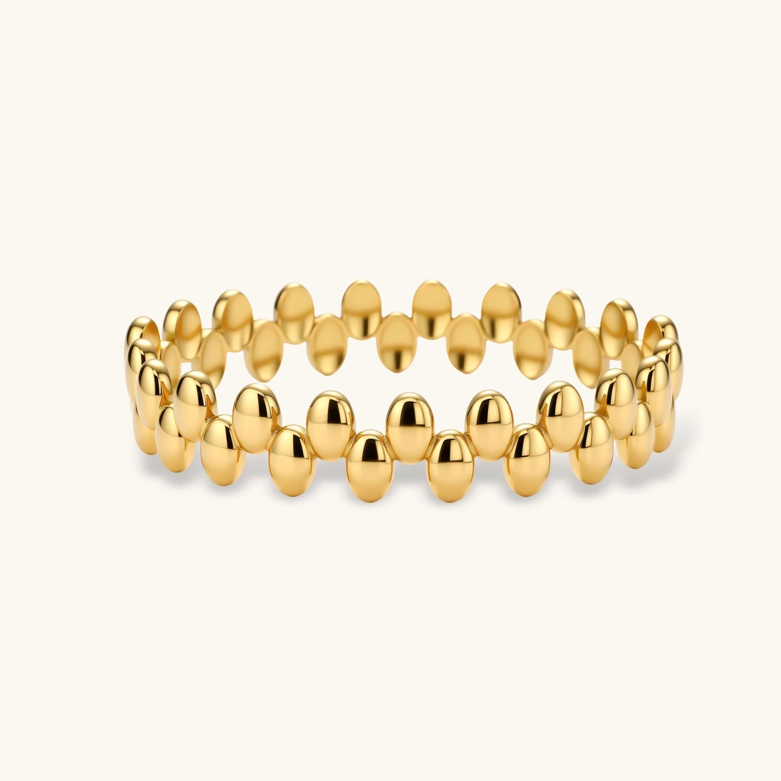 18K gold plated stainless steel bangle with dual rows of polished oval pebble beads on a cream background.