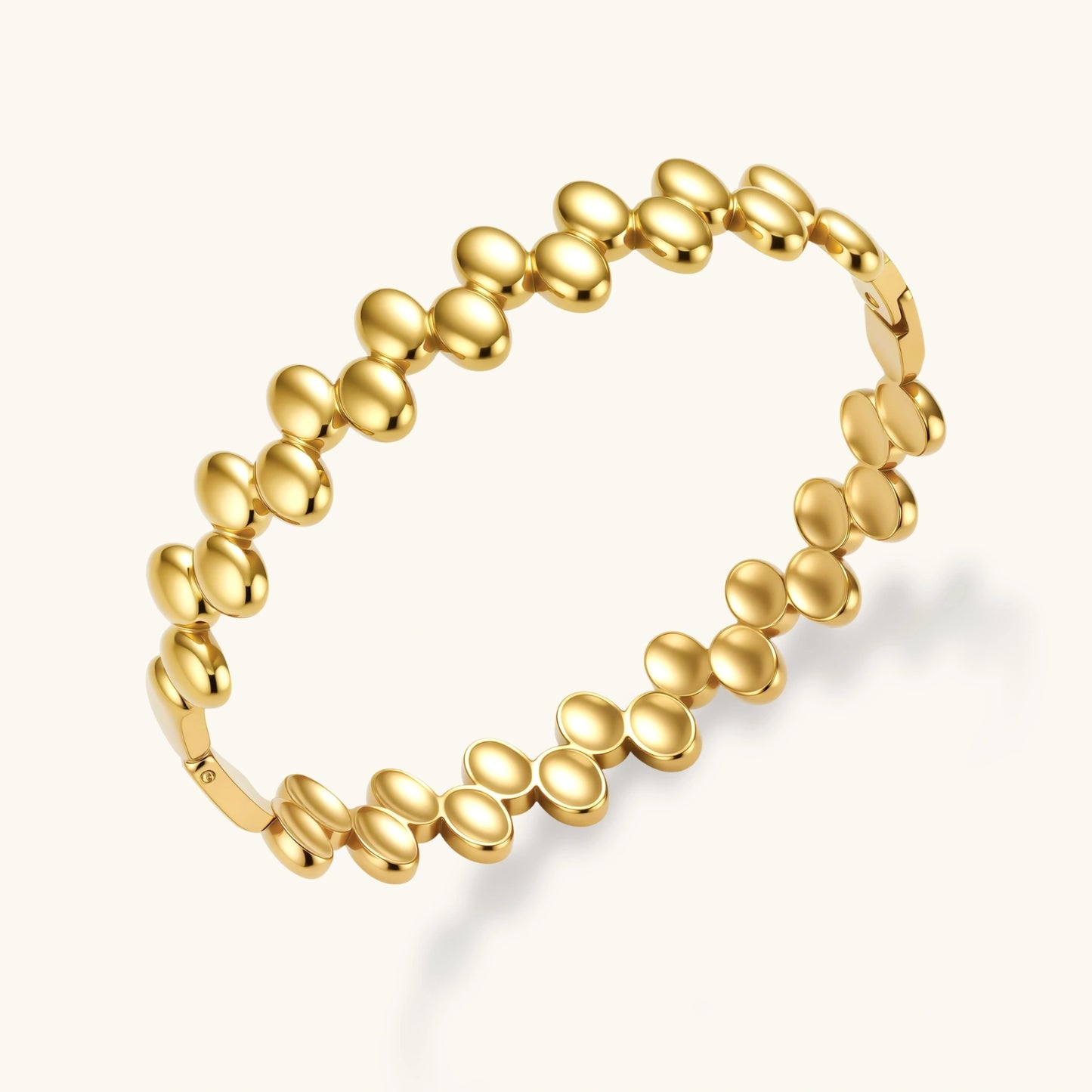 18K gold plated stainless steel bangle with dual rows of polished oval pebble beads on a cream background.